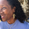 Woman wearing 14k gold earrings with Women's Coalition venus symbol.