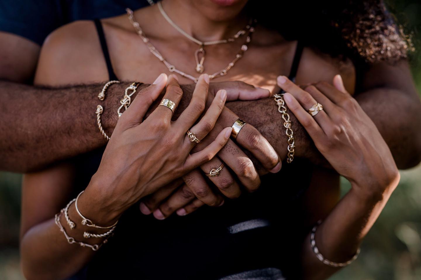 Close-up of interlocked hands with jewelry, focusing on details.