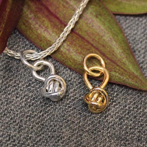 Sterling silver charm and 14k gold charm with ball shaped Crucian knot design.