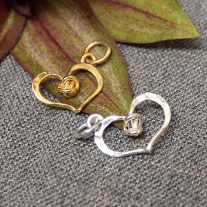 Hammered sterling silver and 14k gold heart shaped charm with love knot design in center.