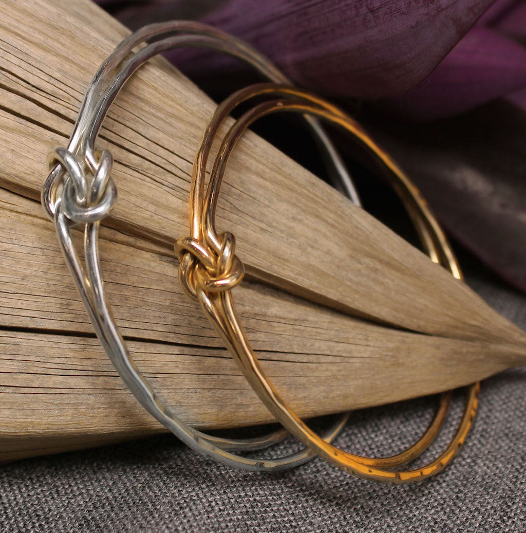 Sterling silver and gold bangles with friendship knot design in center.