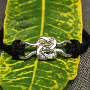Black nylon adjustable cord friendship bracelet with sterling silver friendship knot design in center.