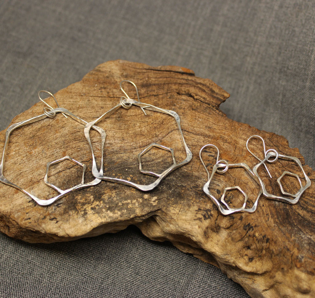 Small and large sterling silver hexagonal earrings with small hexagonal shape inside a larger hexagon..