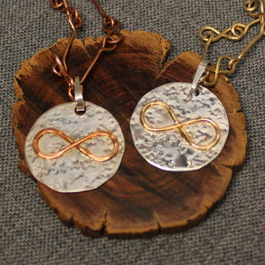 Hammered sterling silver disc pendant with copper or 14k gold infinity symbol in the center.