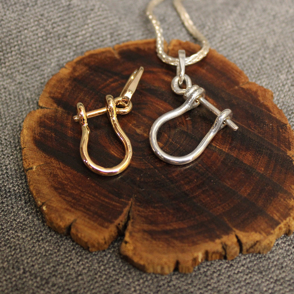 Sterling silver and 14k gold Sailor's Shackle pendants.