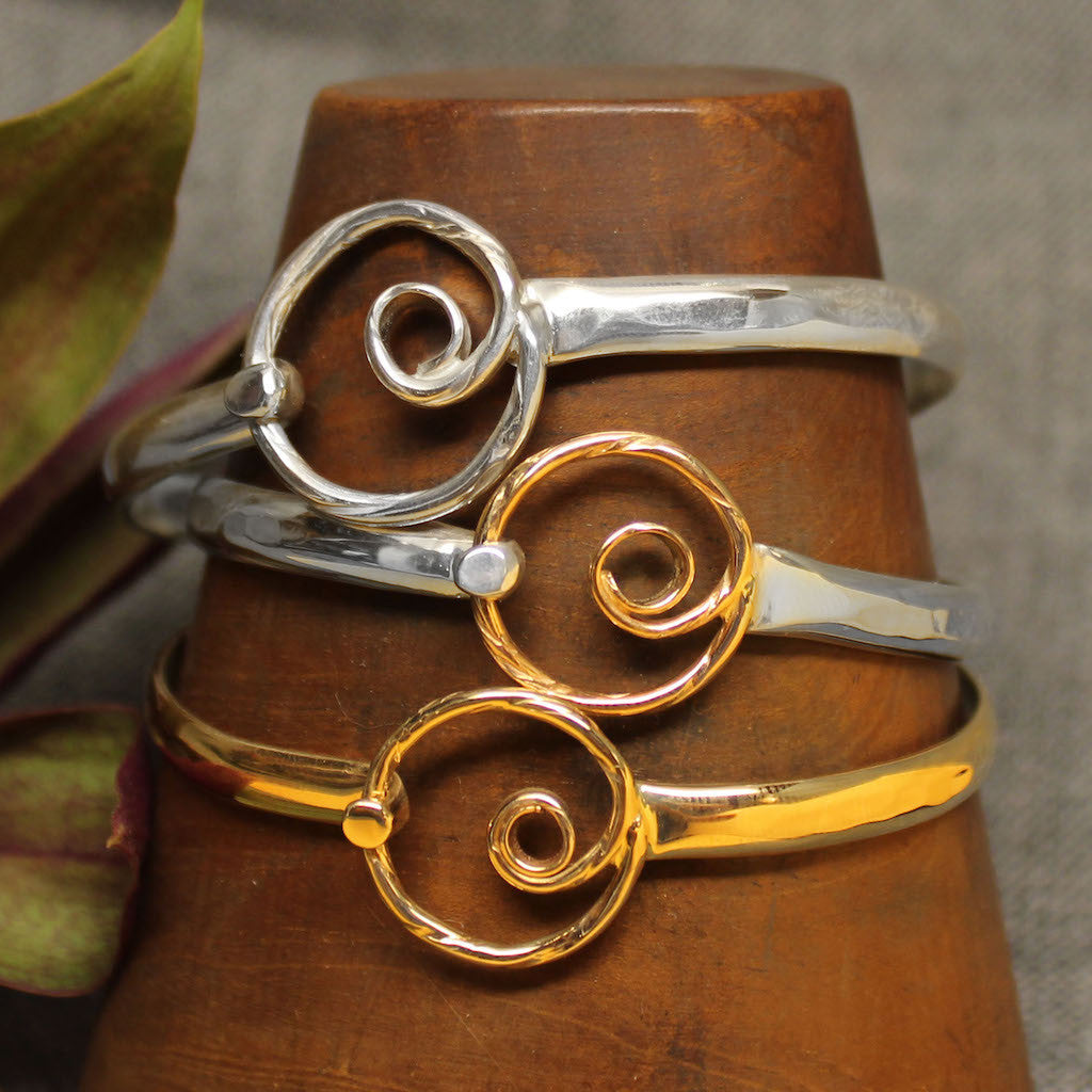 Sterling silver, 14k gold and 2-tone latching bracelets with spiral design in center.