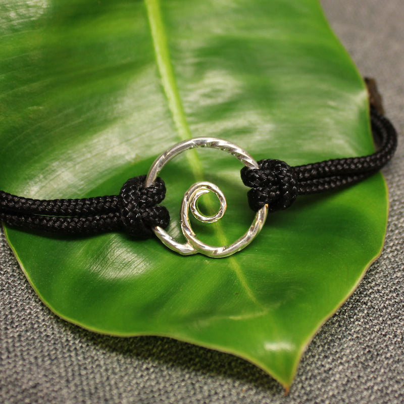Adjustable black nylon cord bracelet with sterling silver spiral in center.